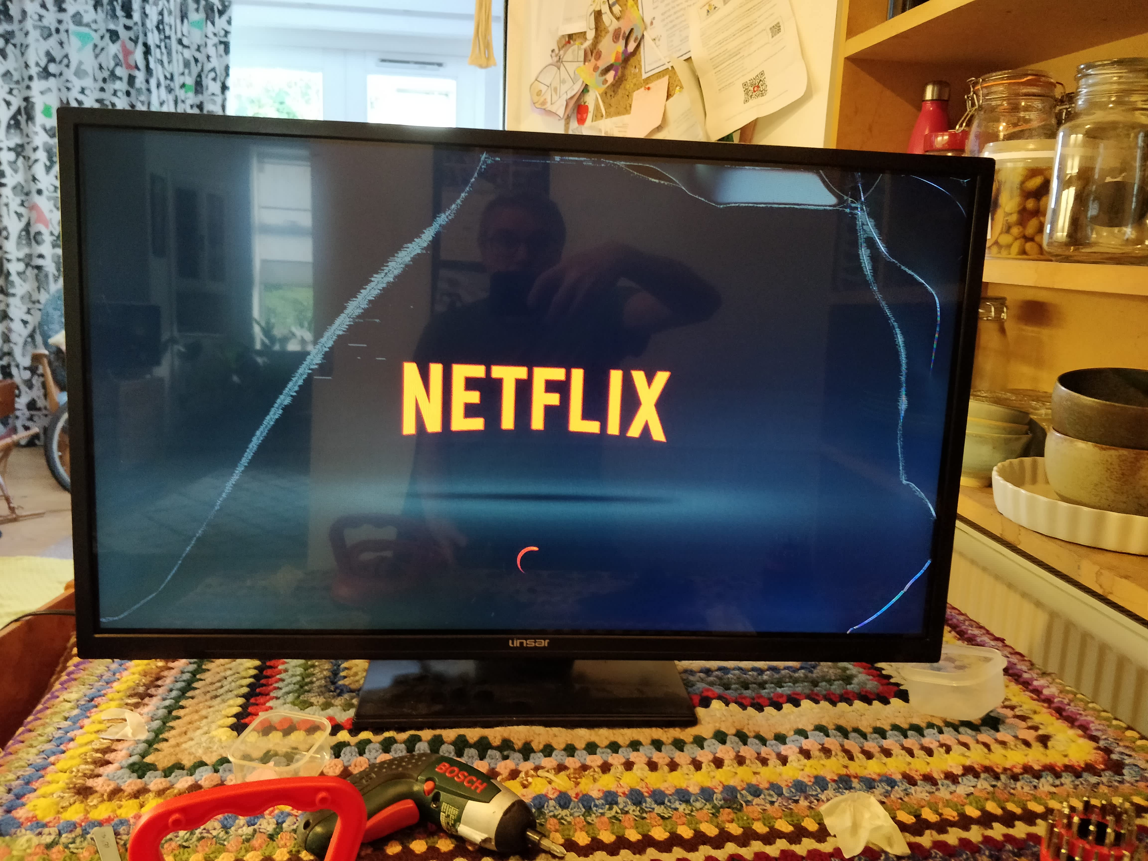 TV showing the Netflix logo. The screen is cracked