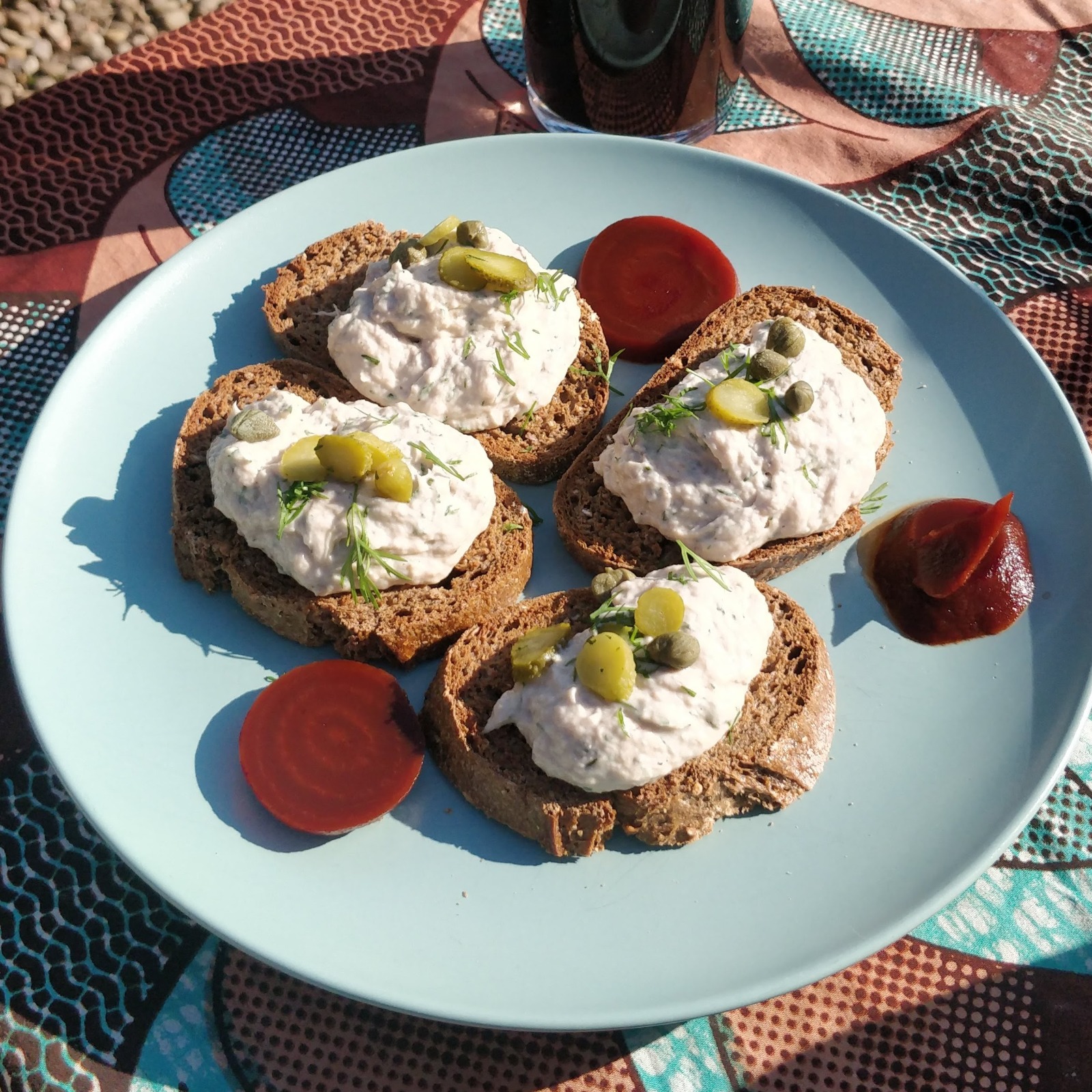 Plate of smoked mackeral pate on toast on a brightly coloured tablecloth in bright sunlight