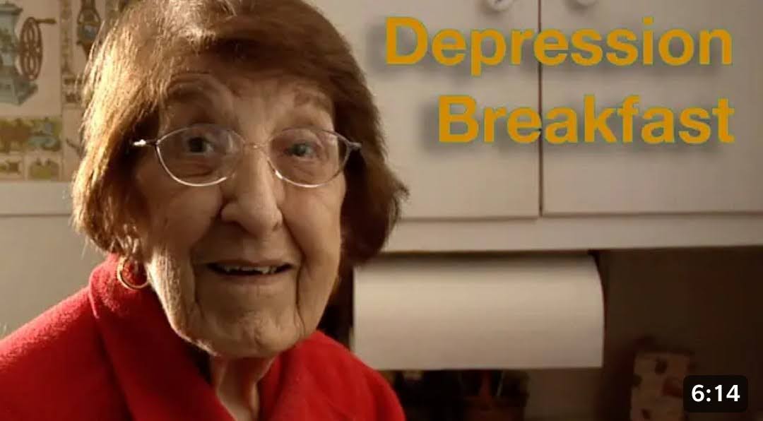 An elderly woman looks at you with a pleasant half-smile, a roll of kitchen towel in the background. Large text reads Depression Breakfast. A time index of 6:14 appears on the bottom right