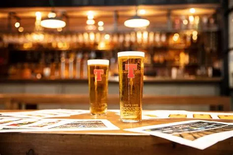 Two pints of lager in Tennents branded glasses on a pub table.