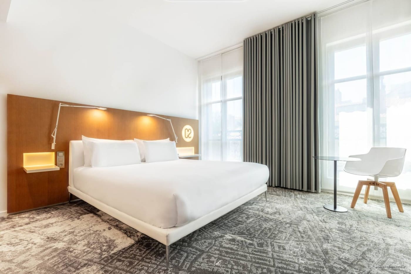 Bedroom at Hôtel C2 with wooden headboard and large window