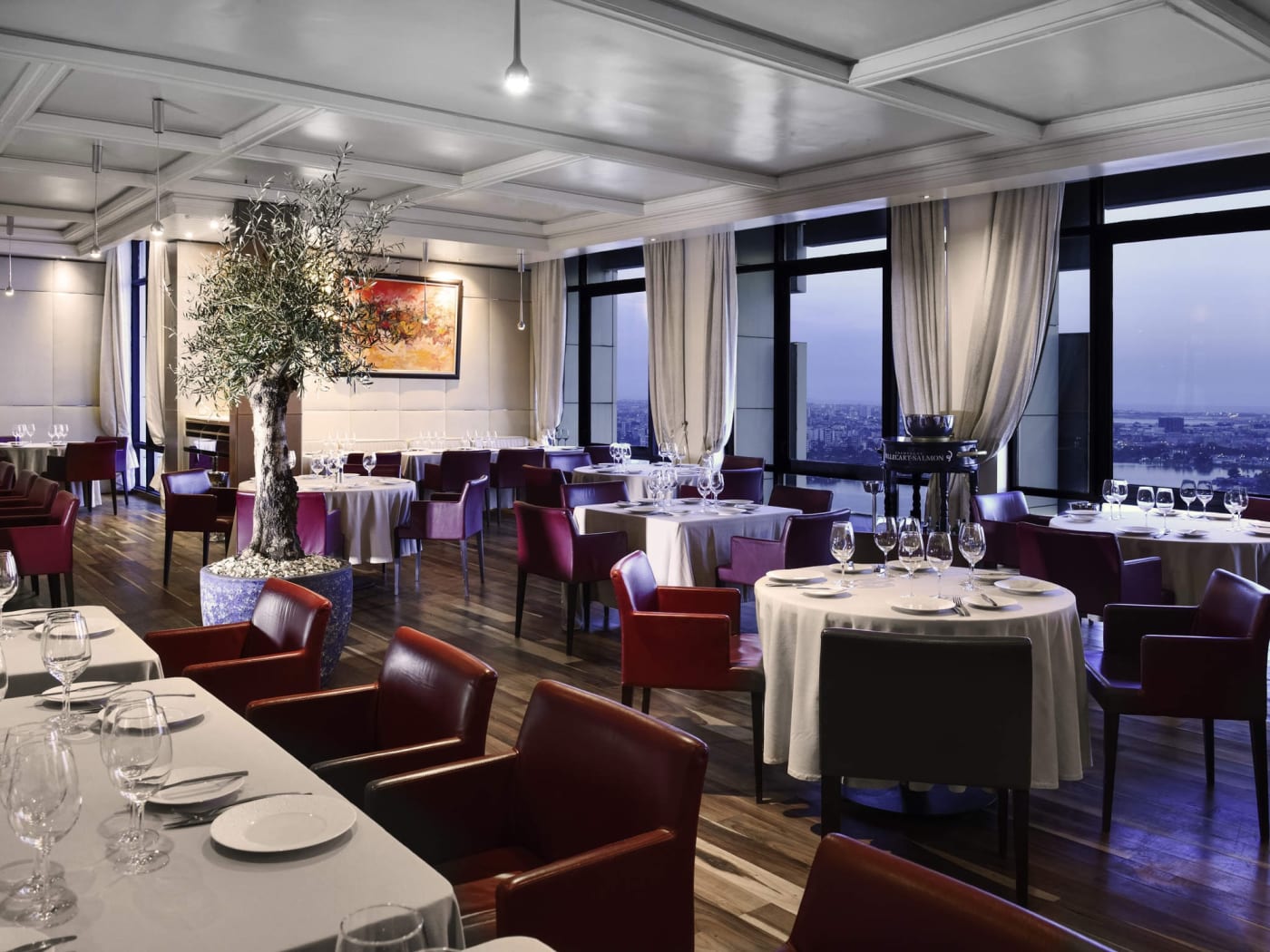 Comedor de un restaurante del Sofitel Abidjan Hôtel Ivoire, con mesas preparadas frente a la laguna