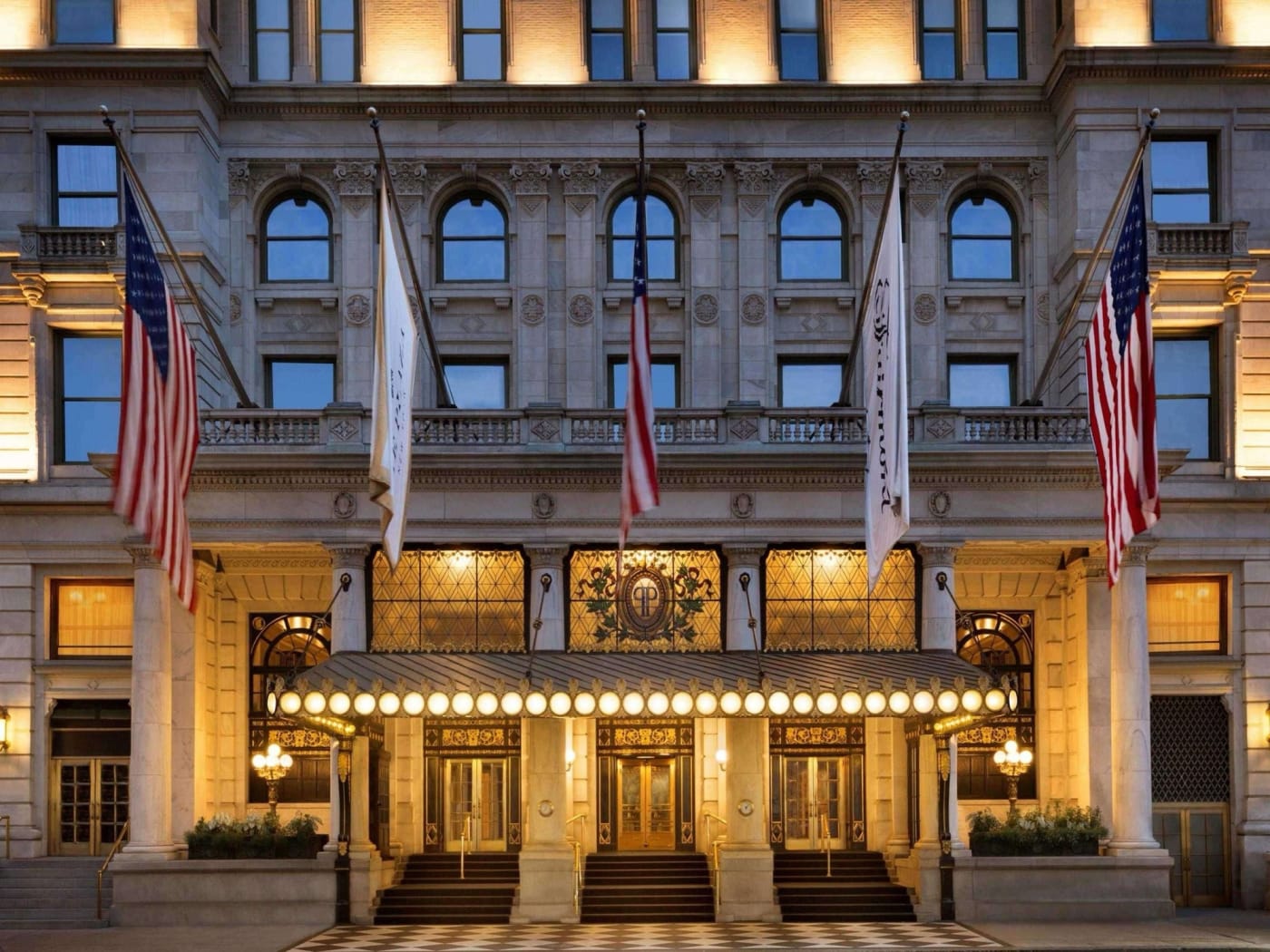 Entrée principale côté Fifth Avenue le soir, marquise éclairée et drapeaux