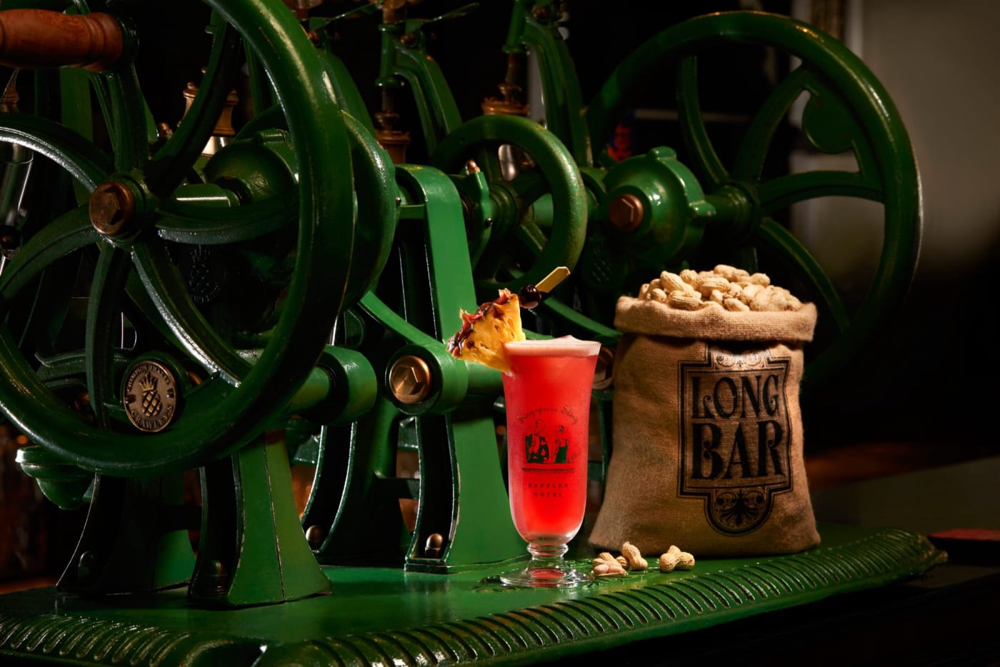 Singapore Sling vor dem mechanischen Shaker und einer Tüte Long Bar Erdnüsse