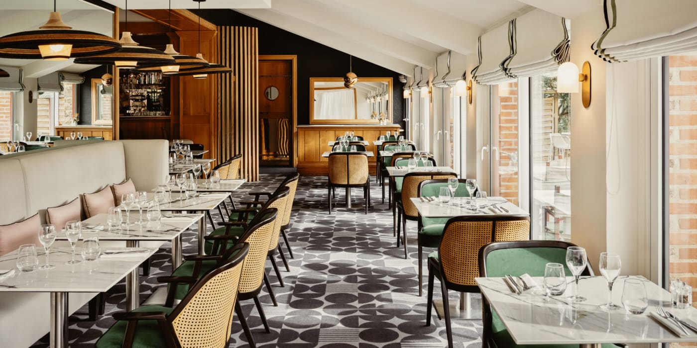 Salle du restaurant Le Club du Domaine de la Bretesche, chaises cannées vertes et suspensions en osier