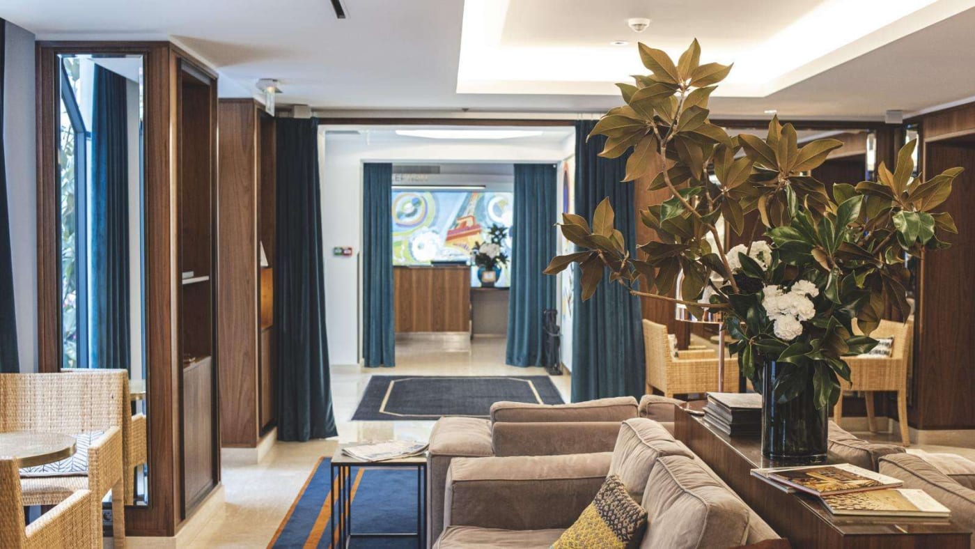 Lobby del Hôtel Eiffel Blomet, con boiseries, cortinas de terciopelo azul y sofás, en la rue Blomet, distrito 15 de París
