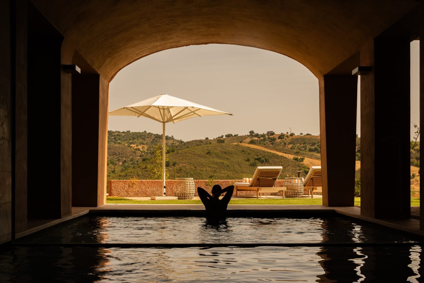 Indoor pool at the Viceroy at Ombria Algarve spa, opening beneath an arch onto the hills of the Algarve