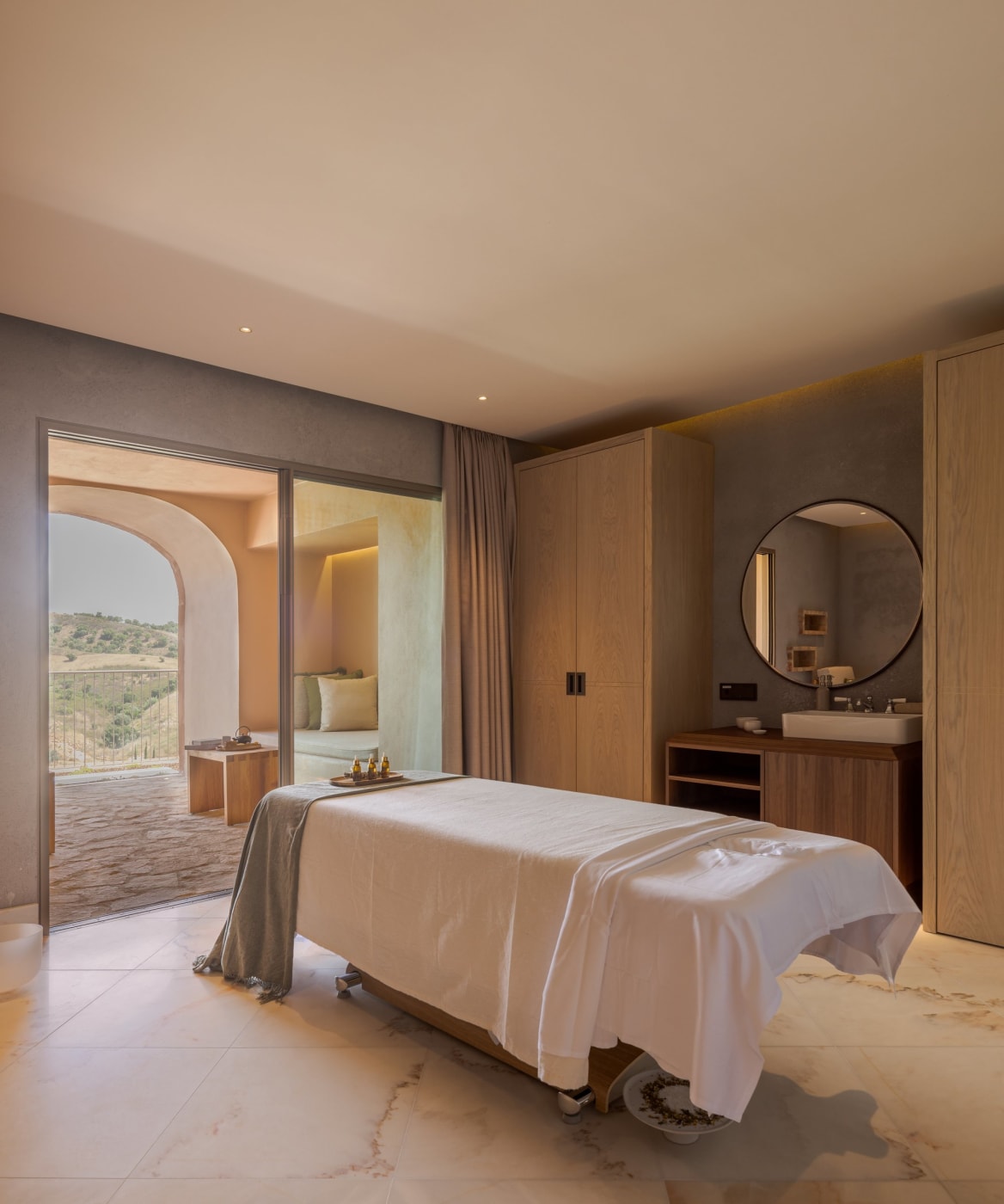 Treatment room at the Viceroy at Ombria Algarve spa, with massage table and a picture window opening onto a patio