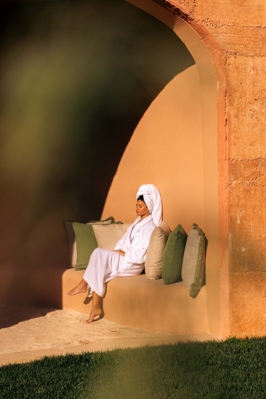 Guest in a bathrobe in an outdoor relaxation alcove at the Viceroy at Ombria Algarve spa