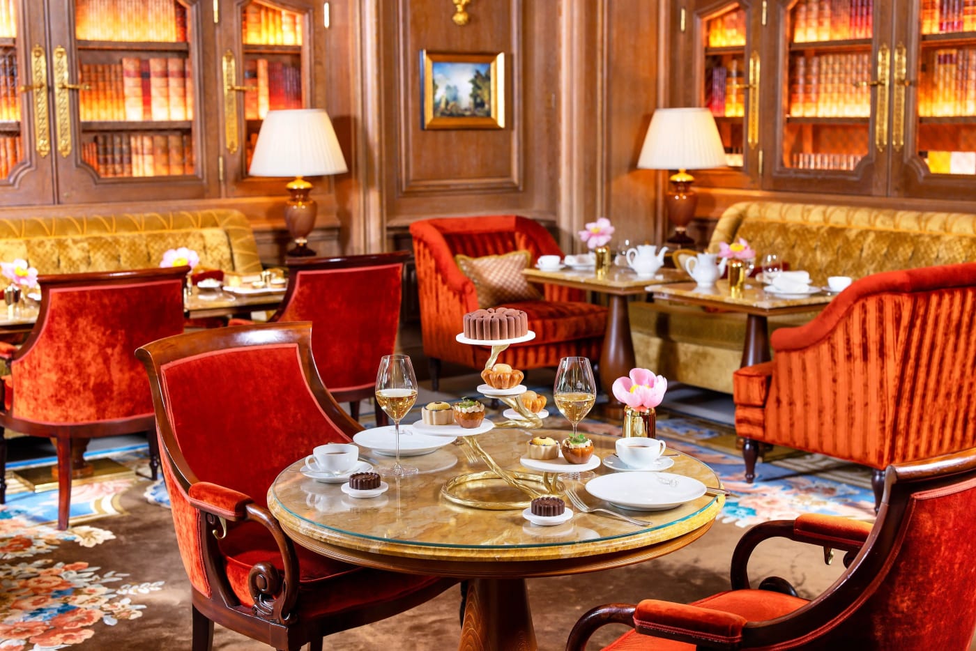 Mesas preparadas para el tea time en el Salon Proust del Ritz Paris, frente a los paneles de madera y los libros antiguos