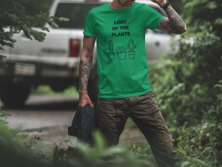 Junger tätowierter Mann mit grünem T-Shirt mit schwarzem Aufdruck "Lord of the plants" und Kakteen-Aufdruck