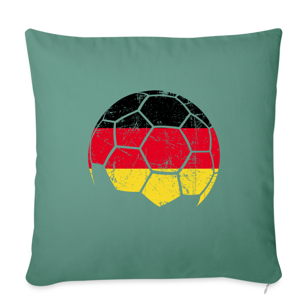 Dekokissen mit Fußballmotiv in den Farben der deutschen Flagge auf grünem Stoff.