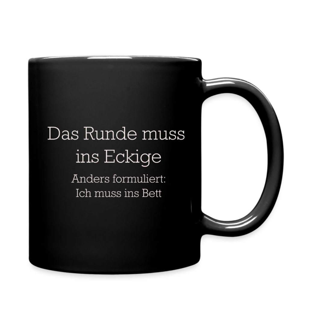 Schwarze Keramiktasse mit weißem Schriftzug „Das Runde muss ins Eckige – anders formuliert: Ich muss ins Bett“ auf einfarbigem Hintergrund.