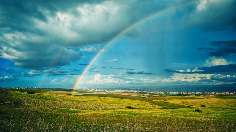 A vast, sunny landscape with a rainbow