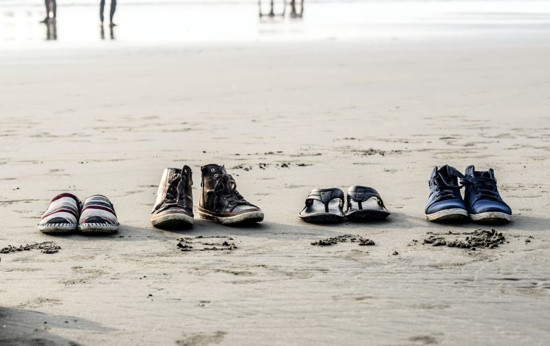 4 different pairs of shoes on a beach