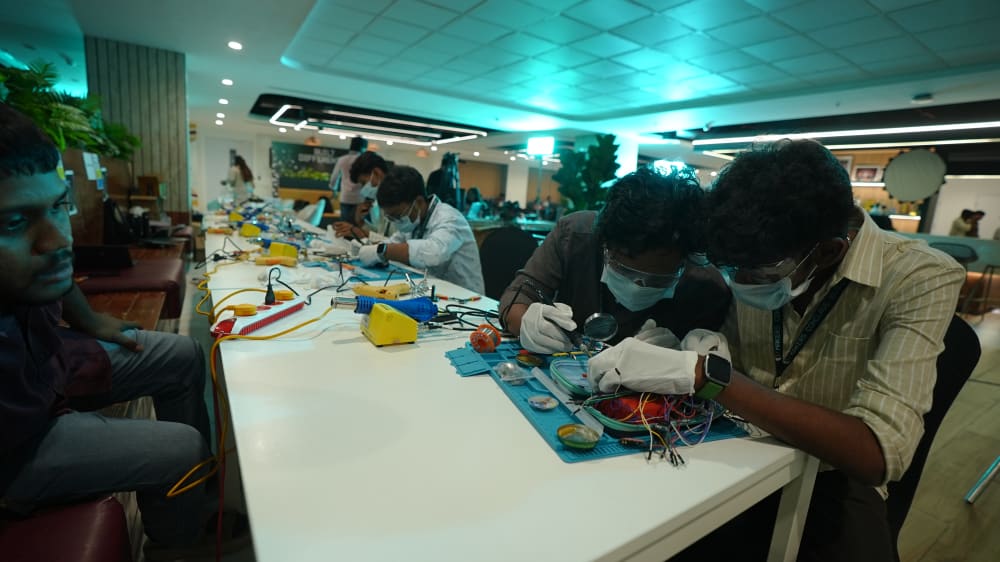 Students in masks and gloves doing precision assembly work on a health tech build