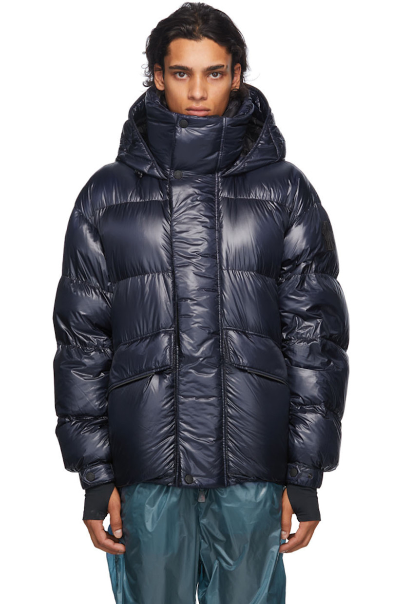 Long sleeve down-filled quilted technical ripstop coat in navy. Bungee-style drawstring at hood. Concealed zip closure with Velcro placket at front. Flap pockets and zippered pockets at waist. Detachable embroidered logo patch in black with Velcro fastening. Adjustable press-stud tab and thumb opening at integrated bonded jersey cuffs. Zippered pocket at interior featuring headphone wire opening. Integrated adjustable harness in black at interior with press-release buckle fastening. 

Supplier color: Blue

Fill: 90% goose down, 10% feathers.