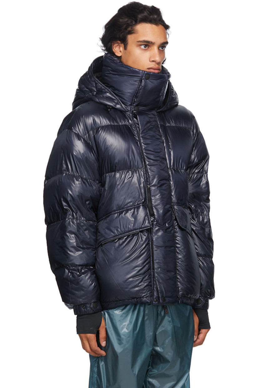 Long sleeve down-filled quilted technical ripstop coat in navy. Bungee-style drawstring at hood. Concealed zip closure with Velcro placket at front. Flap pockets and zippered pockets at waist. Detachable embroidered logo patch in black with Velcro fastening. Adjustable press-stud tab and thumb opening at integrated bonded jersey cuffs. Zippered pocket at interior featuring headphone wire opening. Integrated adjustable harness in black at interior with press-release buckle fastening. 

Supplier color: Blue

Fill: 90% goose down, 10% feathers.