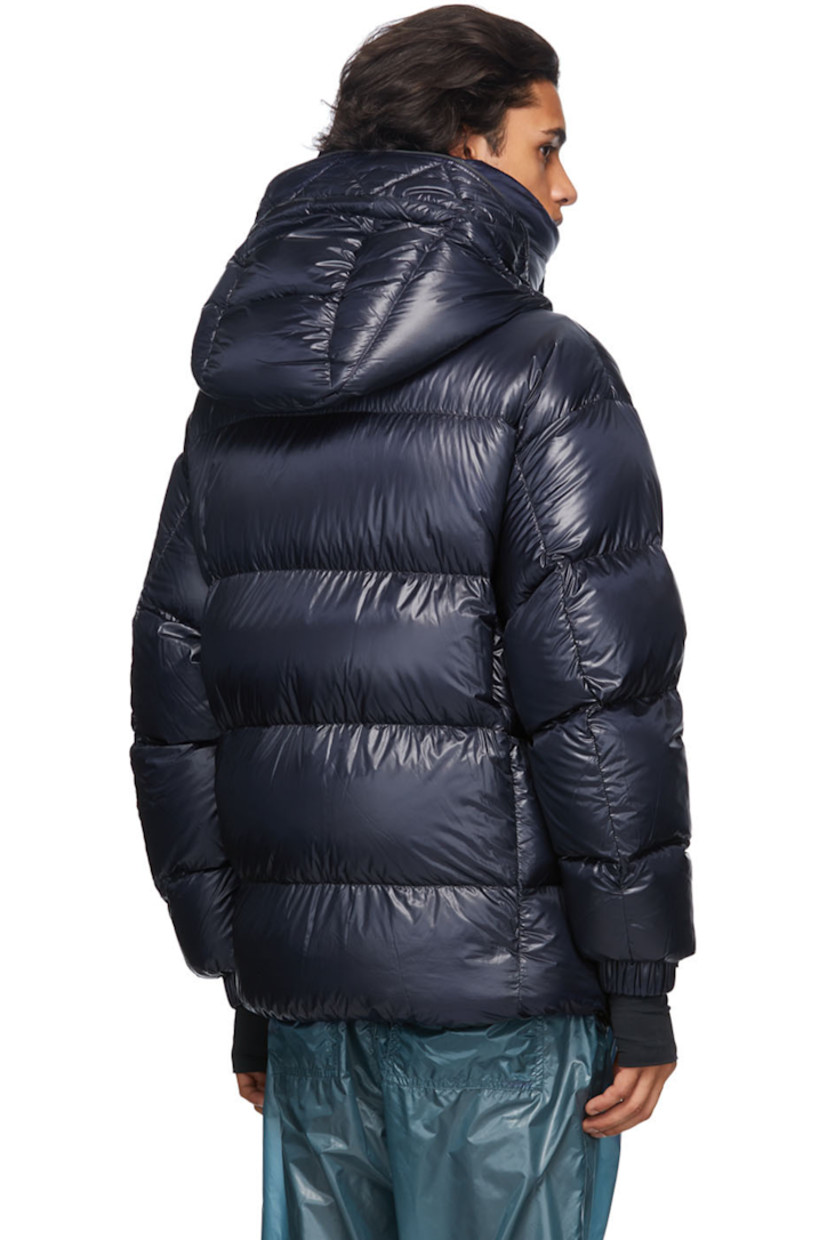 Long sleeve down-filled quilted technical ripstop coat in navy. Bungee-style drawstring at hood. Concealed zip closure with Velcro placket at front. Flap pockets and zippered pockets at waist. Detachable embroidered logo patch in black with Velcro fastening. Adjustable press-stud tab and thumb opening at integrated bonded jersey cuffs. Zippered pocket at interior featuring headphone wire opening. Integrated adjustable harness in black at interior with press-release buckle fastening. 

Supplier color: Blue

Fill: 90% goose down, 10% feathers.