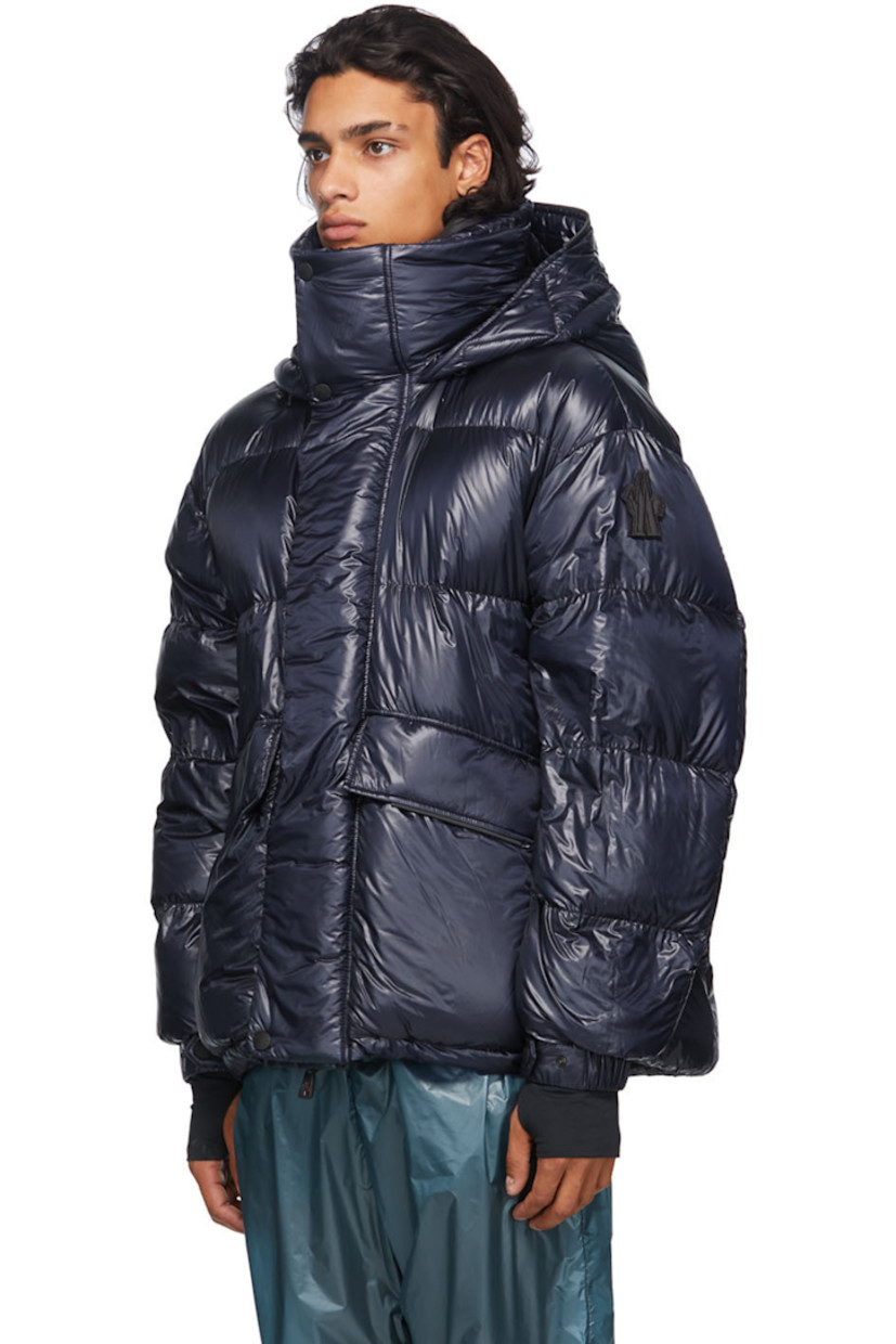 Long sleeve down-filled quilted technical ripstop coat in navy. Bungee-style drawstring at hood. Concealed zip closure with Velcro placket at front. Flap pockets and zippered pockets at waist. Detachable embroidered logo patch in black with Velcro fastening. Adjustable press-stud tab and thumb opening at integrated bonded jersey cuffs. Zippered pocket at interior featuring headphone wire opening. Integrated adjustable harness in black at interior with press-release buckle fastening. 

Supplier color: Blue

Fill: 90% goose down, 10% feathers.