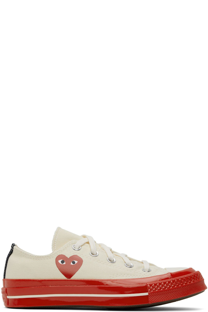Low-top canvas sneakers in off-white.

· Round rubber cap toe
· Lace-up closure
· Logo graphic printed at outer side
· Eyelet vents at inner side
· Webbing trim in black at heel
· Logo embossed at heel 
· Rubber midsole in red
· Treaded rubber outsole in brown

Part of the Comme des Garçons Play x Converse collaboration.

Supplier color: Off white