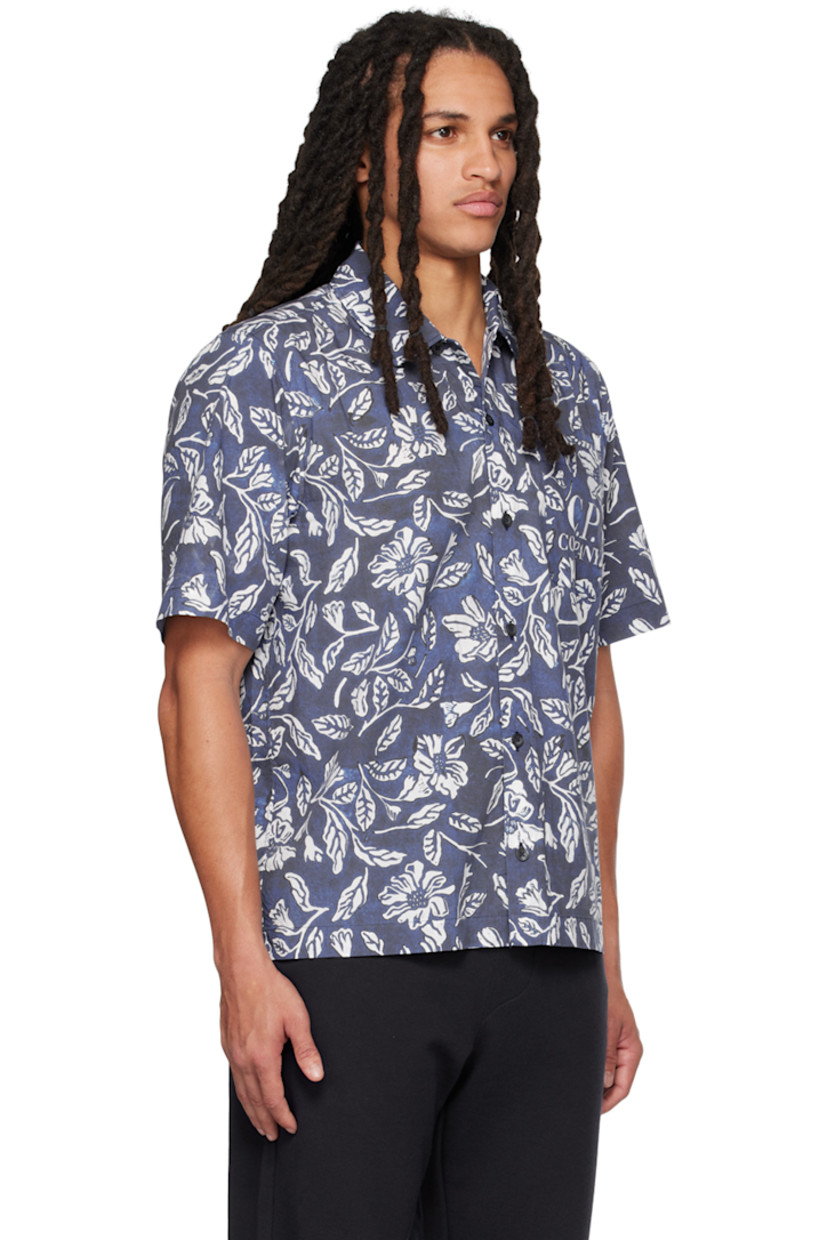 Garment-dyed cotton poplin shirt. Floral pattern and logo printed throughout. 

· Spread collar
· Button closure
· Patch pocket
· Logo-engraved black hardware

Supplier color: Medieval blue