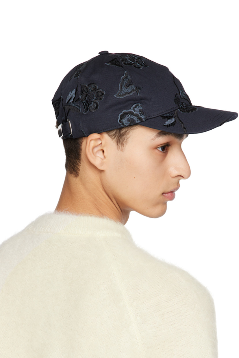 Cotton twill cap in navy. Floral pattern embroidered throughout. 

· Curved brim
· Adjustable cinch strap at back face
· Grosgrain browband
· Cotton twill lining

Supplier color: Navy