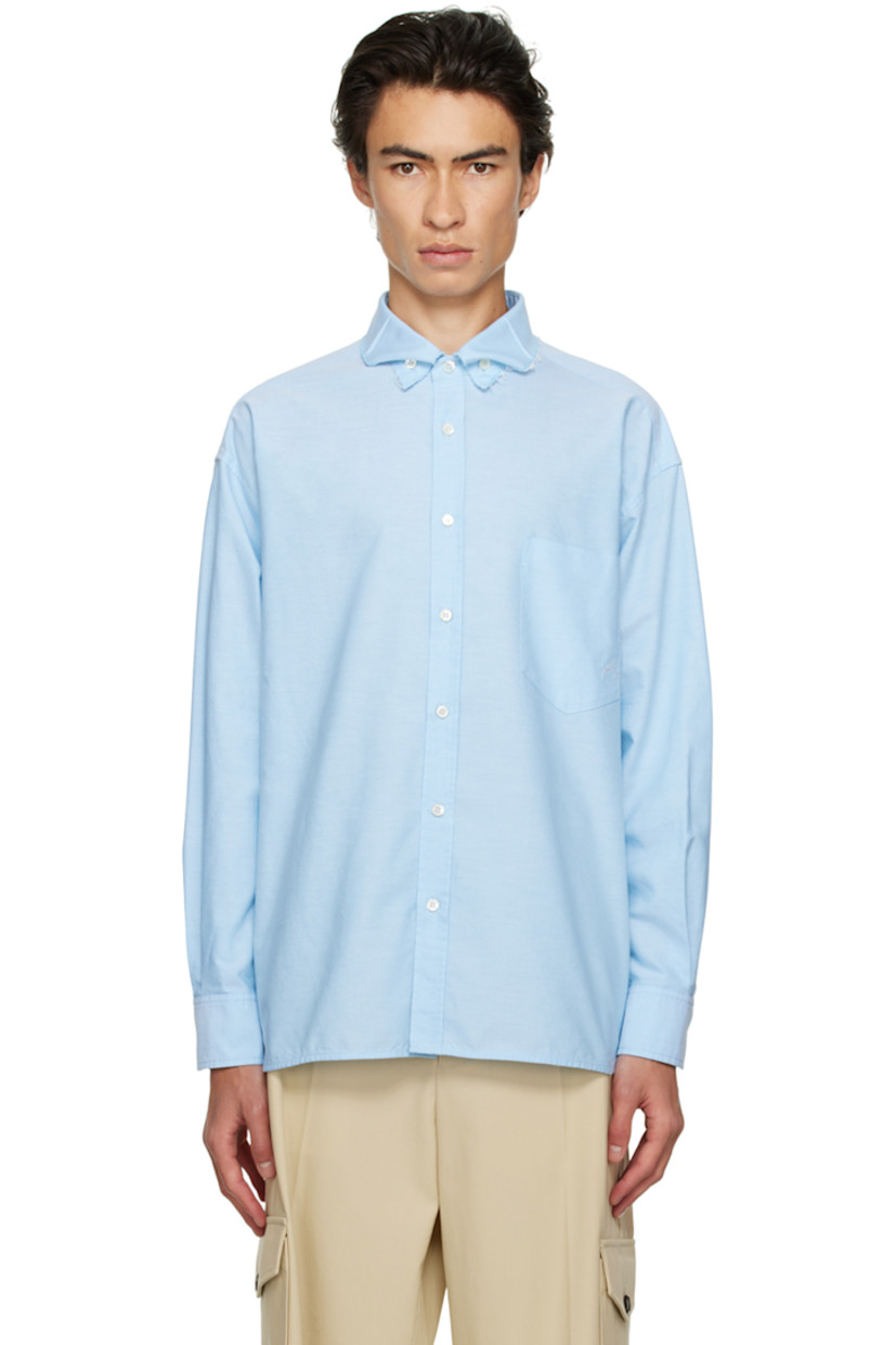 Cotton oxford cloth shirt. 

· Raw edge at spread collar
· Button closure
· Patch pocket 
· Logo embroidered at chest
· Shirttail hem
· Adjustable single-button barrel cuffs
· Box pleat at back 
· Mother-of-pearl hardware

Supplier color: Sky blue