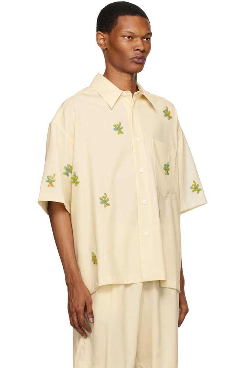 Stretch virgin wool twill shirt. Graphic appliqués throughout.

· Spread collar
· Button closure
· Patch pocket
· Cropped hem
· Dropped shoulders
· Inverted pleat at back yoke 

Supplier color: Ivory