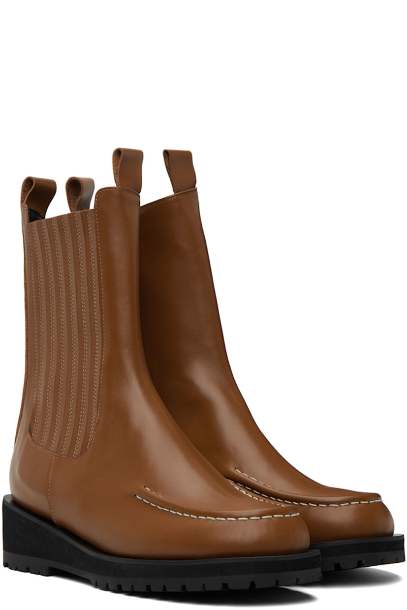 Calf-high buffed leather boots in brown.

· Moc toe
· Pull-loops at collar
· Elasticized gusset at outer side
· Zip closure at inner side
· Foam rubber platform midsole
· Treaded rubber outsole
· Heel: H1.75 in

Supplier color: Brown