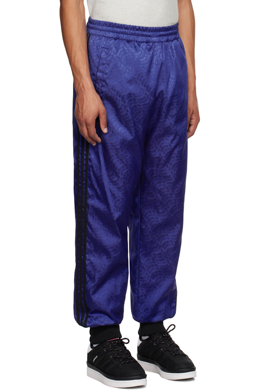 Down-filled nylon twill trousers. Logo pattern throughout. 

· Concealed drawstring at elasticized waistband 
· Two-pocket styling 
· Rib knit cuffs 
· Jersey stripes at outseams 
· Rubberized logo patch at outseam 
· Rubberized logo appliqué at back 
· Full quilted satin lining 

Part of the Moncler Genius x adidas Originals collaboration.

Supplier color: Blue 

Fill: 90% goose down, 10% feathers.