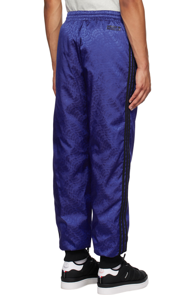 Down-filled nylon twill trousers. Logo pattern throughout. 

· Concealed drawstring at elasticized waistband 
· Two-pocket styling 
· Rib knit cuffs 
· Jersey stripes at outseams 
· Rubberized logo patch at outseam 
· Rubberized logo appliqué at back 
· Full quilted satin lining 

Part of the Moncler Genius x adidas Originals collaboration.

Supplier color: Blue 

Fill: 90% goose down, 10% feathers.