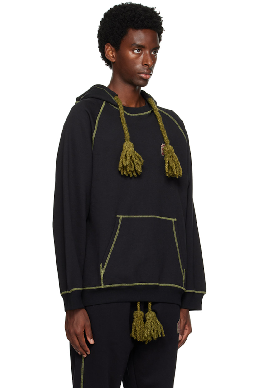 Cotton-blend fleece hoodie. 

· Hand-woven awassi wool Bedouin tassels at hood
· Hand-stitched tatreez embroidery at chest
· Kangaroo pocket
· Rib knit hem and cuffs
· Raglan sleeves
· Contrast stitching in green

Supplier color: Black