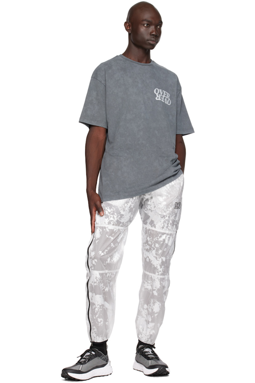 Nylon taffeta track pants. Graphic pattern throughout.

· Paneled construction
· Drawstring at elasticized waistband
· Two-pocket styling
· Logo print at front
· Elasticized cuffs
· Zip vent at outseams 
· Logo flag at back waistband
· Partial mesh lining

Supplier color: White foil