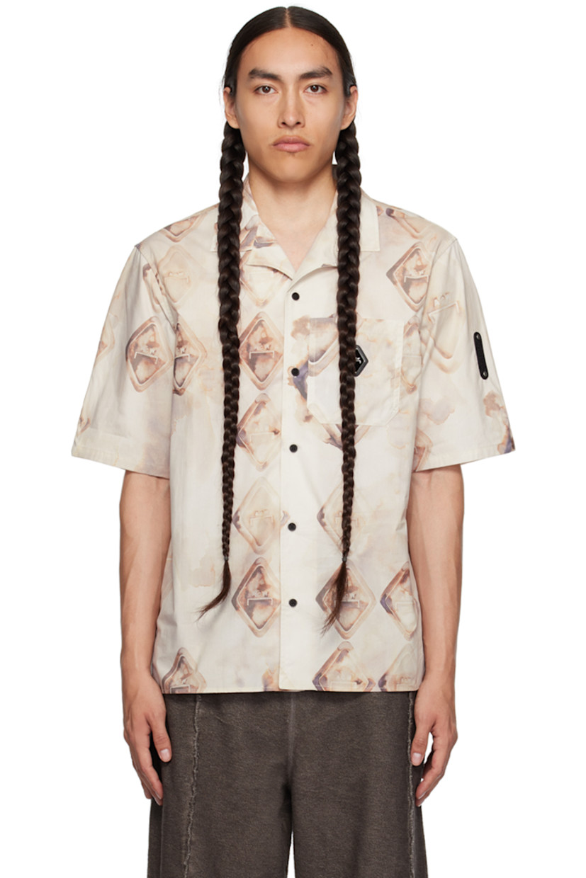Cotton poplin shirt. Graphic and logo pattern printed throughout. 

· Open spread collar
· Button closure
· Logo plaque and patch pocket at chest
· Tennis-tail hem
· Rubberized logo patch at sleeve
· Central vent at back hem

Supplier color: Orange/Amber