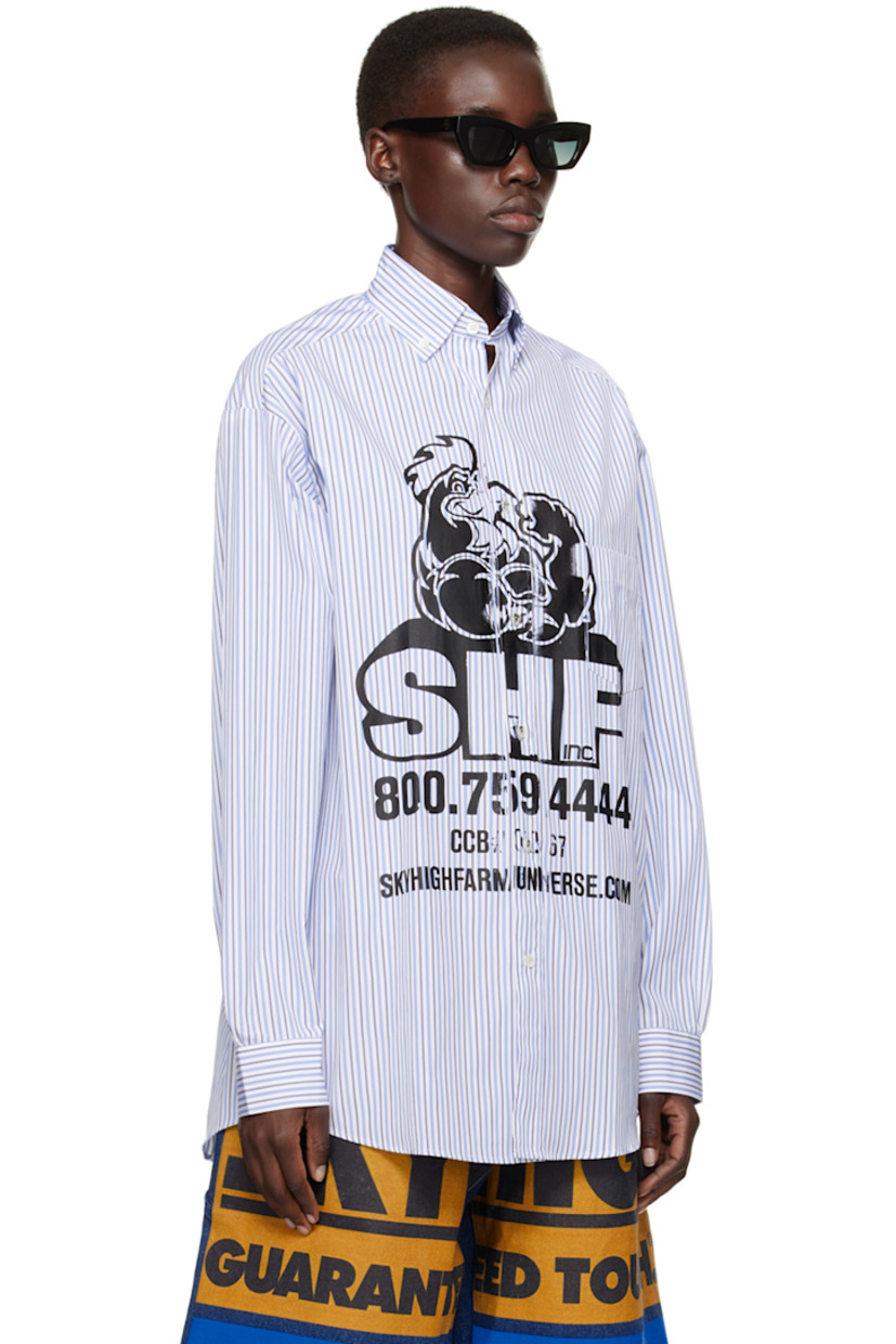 Deadstock cotton poplin shirt. Stripes throughout.

· Buttoned spread collar
· Button closure
· Patch pocket
· Logo graphic printed at front
· Shirttail hem
· Dropped shoulders
· Single-button barrel cuffs
· Box pleat at back yoke

Each item is unique. Please note that coloration and finishings may vary.

Supplier color: Blue