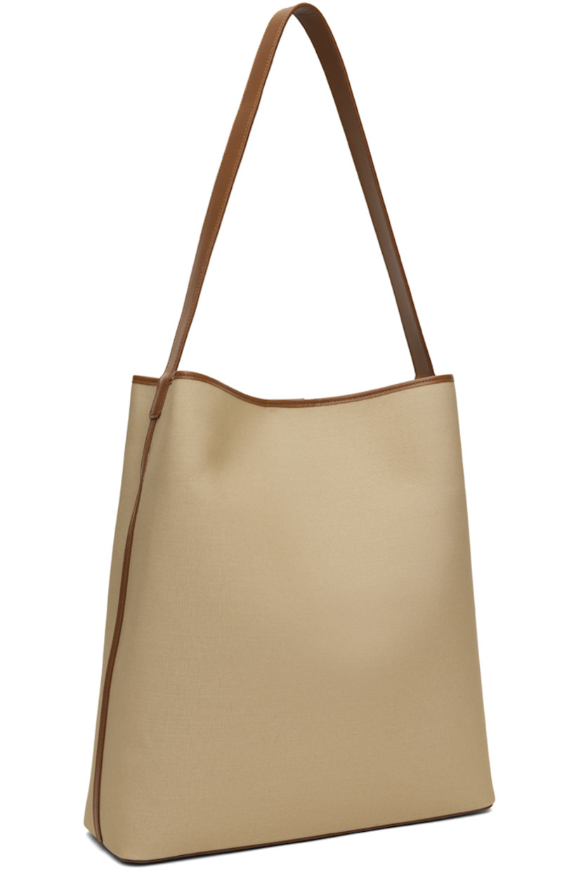 Canvas tote in beige.

· Buffed calfskin trim throughout
· Fixed shoulder strap
· Bumper studs at base
· Magnetic closure
· Laptop compartment at interior
· Grained faux-leather lining
· H14.5" x W13.25" x D4.25"

Supplier color: Canvas