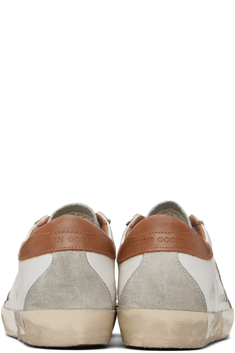 Handcrafted low-top buffed leather sneakers in white and brown. 

· Smudging throughout
· Lace-up closure
· Perforated detailing at tongue and sides
· Padded collar
· Signature star appliqué and text printed at outer side
· Logo embossed at heel tab
· Suede and terrycloth lining
· Treaded rubber sole

Available exclusively at SSENSE.

Supplier color: White/Brown
