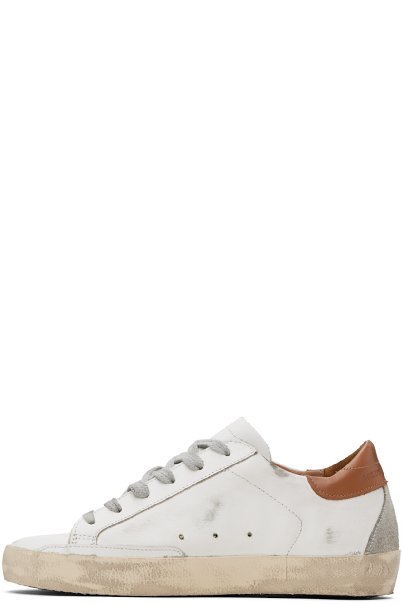 Handcrafted low-top buffed leather sneakers in white and brown. 

· Smudging throughout
· Lace-up closure
· Perforated detailing at tongue and sides
· Padded collar
· Signature star appliqué and text printed at outer side
· Logo embossed at heel tab
· Suede and terrycloth lining
· Treaded rubber sole

Available exclusively at SSENSE.

Supplier color: White/Brown