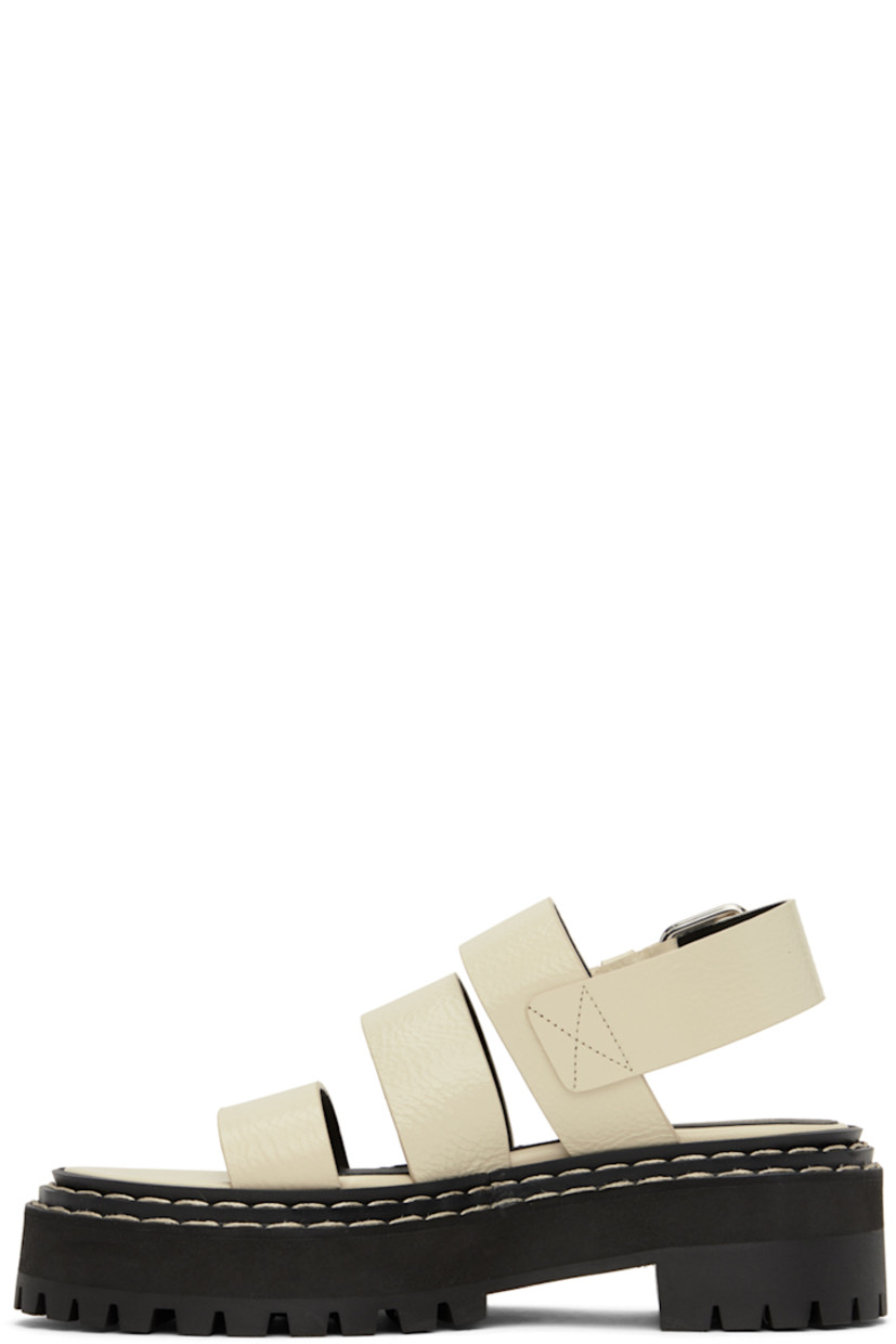 Grained calfskin sandals in off-white. 

· Straps at vamp
· Pin-buckle ankle strap
· Logo printed at leather footbed
· Topstitching at tiered welt
· Foam rubber platform midsole
· Lug rubber sole
· Platform: H1.25"
· Heel: H1.75"

Supplier color: Natural