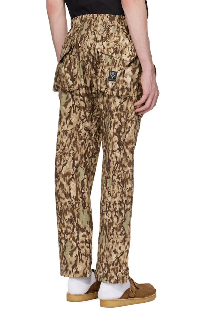 Polyester ripstop trousers. Camouflage pattern printed throughout. 

· Paneled construction
· Integrated webbing cinch belt at waist
· Elasticized waistband 
· Four-pocket styling
· D-ring and bellows pockets at front
· Zip pockets at front
· Logo patch at back pocket

Supplier color: Horn camo