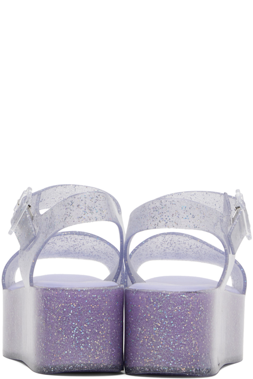 Lightweight glittered transparent MelFlex® PVC sandals in blue.

· Open toe
· Pin-buckle ankle-strap
· Logo embossed at outer side
· Logo stamp at padded Grenflex® footbed
· Treaded PVC platform sole
· Platform: H2"

Supplier color: Clear