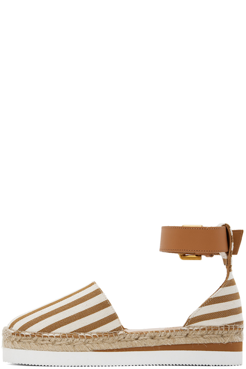 Canvas espadrilles in brown and off-white.

· Stripes throughout
· Buffed leather pin-buckle ankle strap
· Logo embossed at padded calfskin footbed
· Suede and buffed calfskin lining
· Blanket stitching at welt
· Braided jute midsole
· Treaded foam rubber platform sole
· Platform: H1.5"

Supplier color: Tan