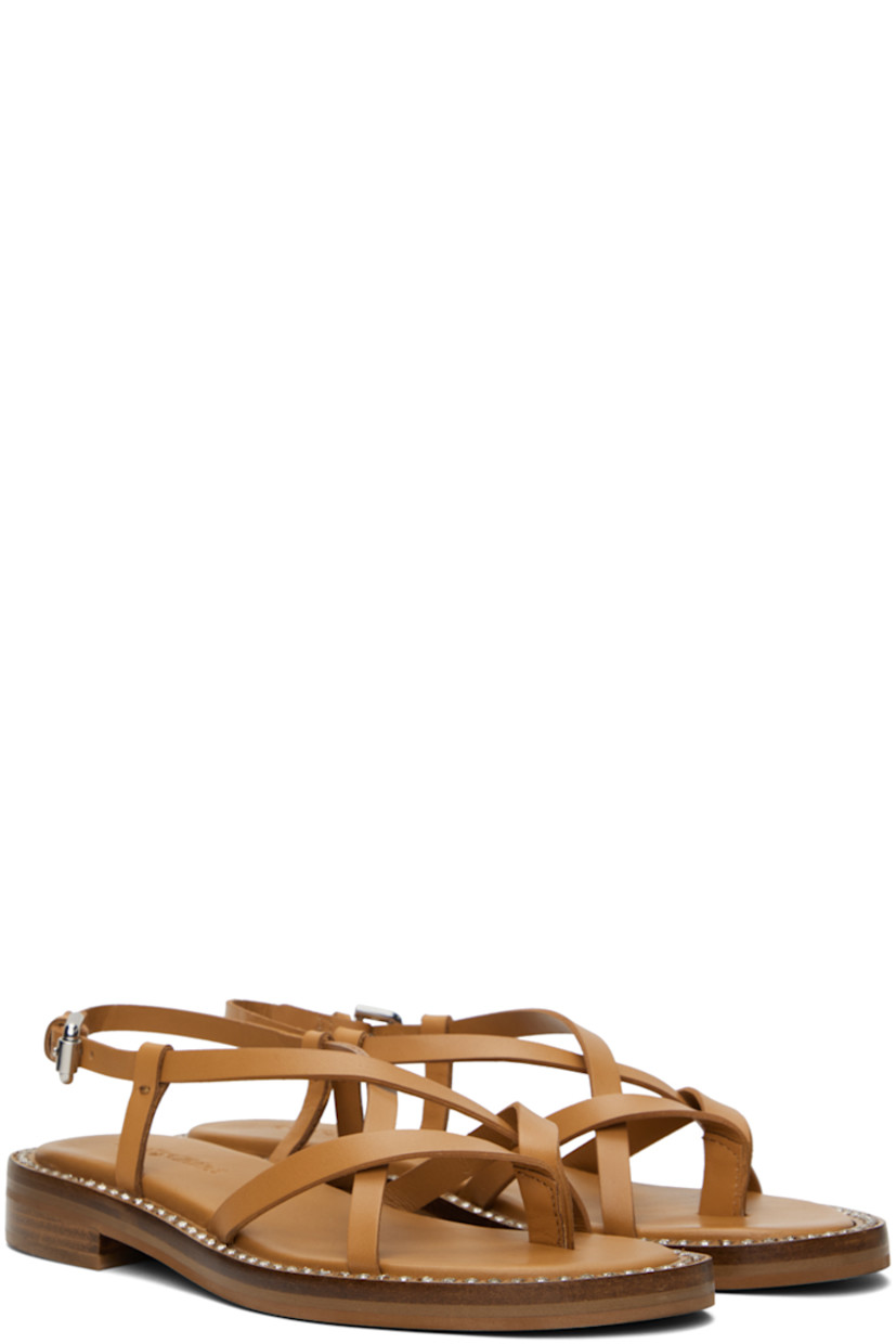 Buffed calfskin flat sandals in tan.

· Thong-style strap at open toe
· Criss-crossing straps at vamp
· Pin-buckle slingback strap
· Logo embossed at padded calfskin footbed
· Crystal-cut detailing at welt
· Stacked leather block heel with rubber injection
· Leather sole
· Heel: H1"

Supplier color: Tan