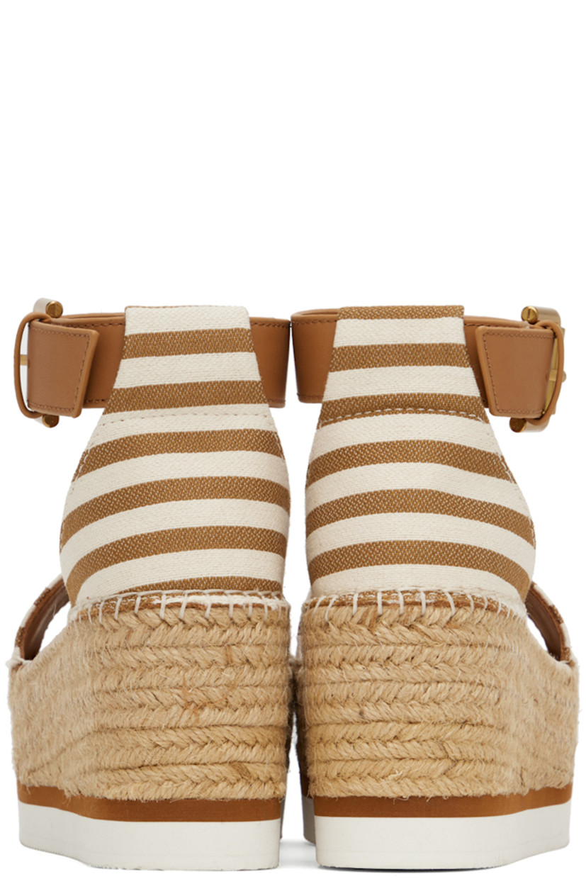 Canvas flat sandals in tan and white.

· Open toe
· Calfskin pin-buckle ankle strap
· Buffed calfskin footbed
· Blanket stitching at welt
· Braided jute platform midsole
· Treaded foam rubber sole
· Platform: H2.25"

Supplier color: Tan