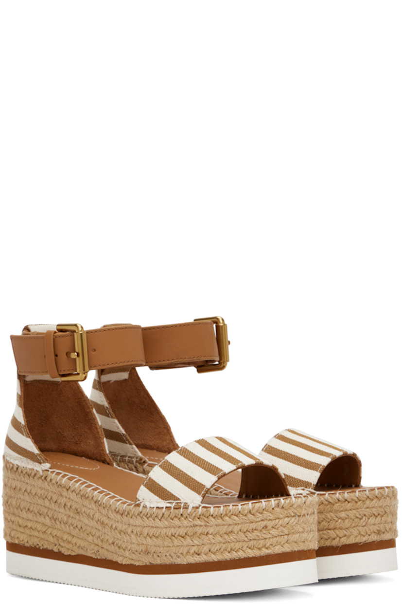 Canvas flat sandals in tan and white.

· Open toe
· Calfskin pin-buckle ankle strap
· Buffed calfskin footbed
· Blanket stitching at welt
· Braided jute platform midsole
· Treaded foam rubber sole
· Platform: H2.25"

Supplier color: Tan