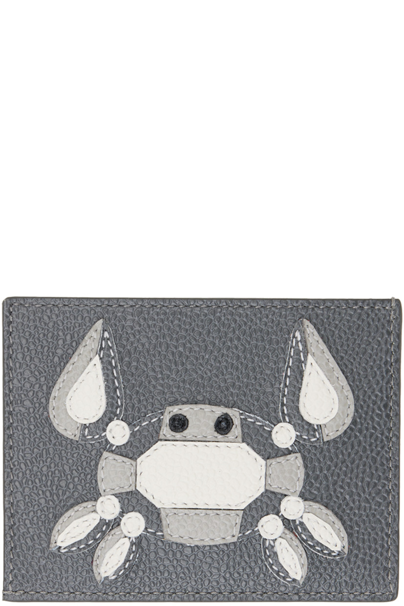 Pebble grained leather card holder in gray. 

· Gold-tone logo stamp at face
· Tricolor grosgrain flag at face
· Graphic appliqué at back face
· Three card slots
· One central note slot
· Faille lining
· H3" x W4"

Supplier color: Dark grey