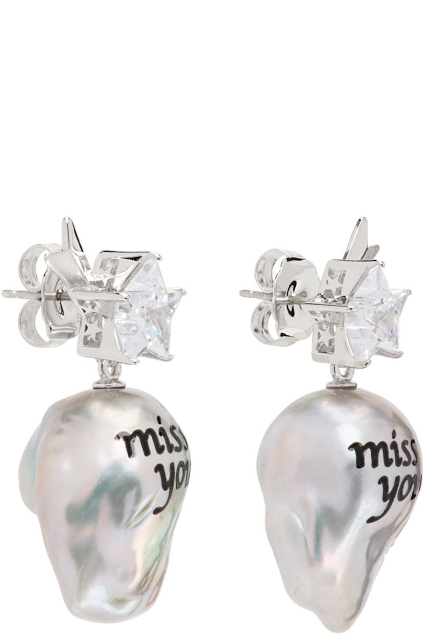 Pair of drop earrings in rhodium-plated brass.

· Graphic with cubic zirconia at face
· Baroque freshwater pearl with printed text
· Post-stud fastening
· H1.5" x W0.75"

Supplier color: White