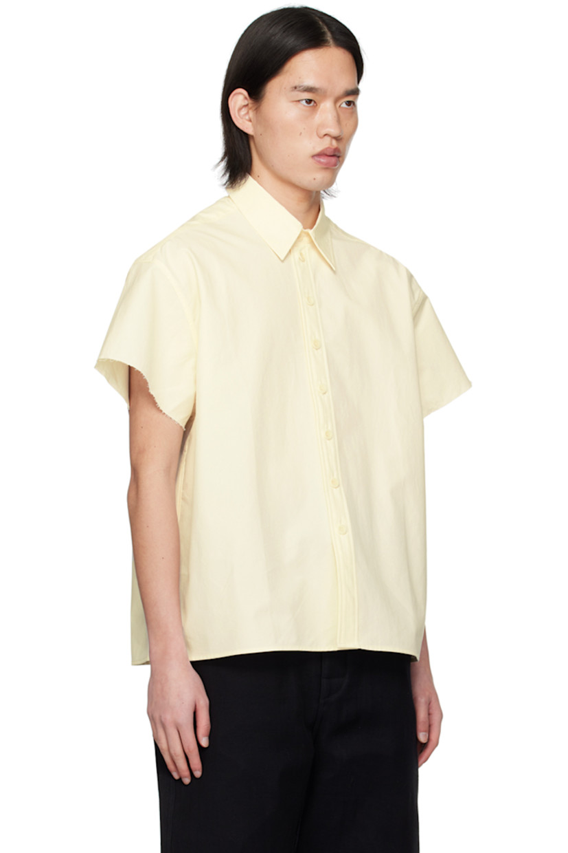 Cotton poplin shirt.

· Spread collar
· Button closure
· Shirttail hem
· Raw edge at cuffs
· Logo embroidered at back collar
· Inverted box pleat at back yoke 

Supplier color: Natural