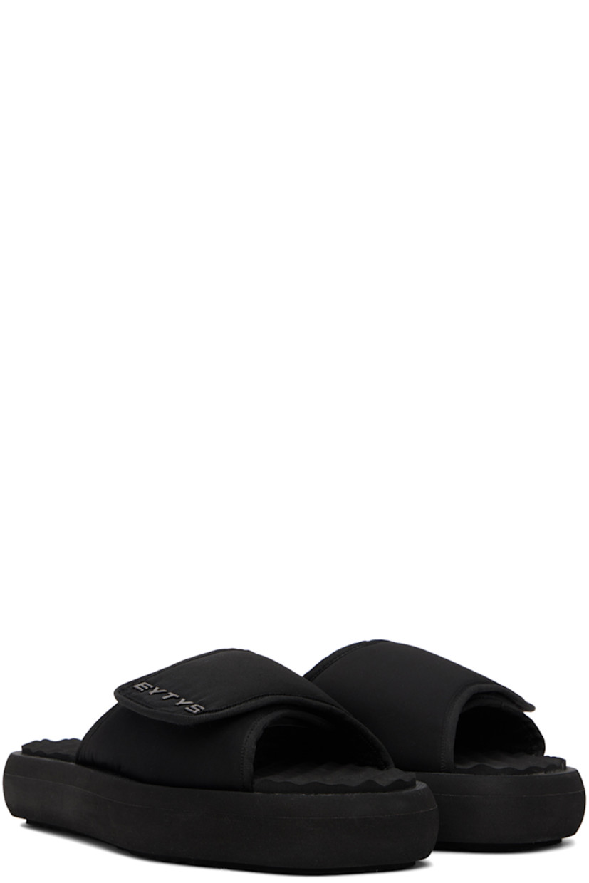 Padded nylon twill slip-on sandals in black.

· Open square toe
· Velcro strap at vamp
· Logo hardware at vamp
· Rubberized logo patch at foam footbed
· Terrycloth lining
· Treaded EVA foam platform sole
· Platform: H1.5"

Supplier color: Nylon black